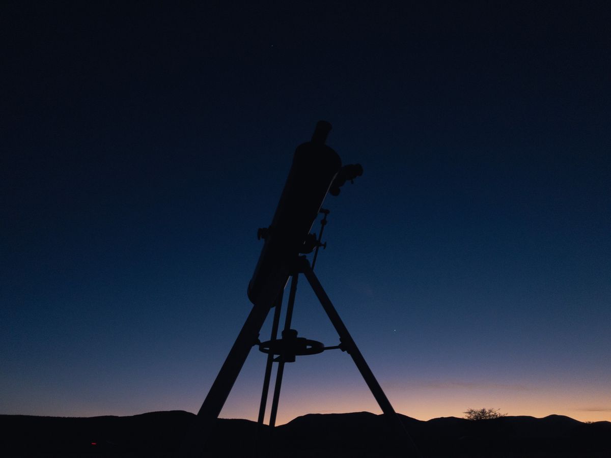 Why stars twinkle but planets don't: a telescope silhouette under a star-filled night sky, showing practical stargazing implications