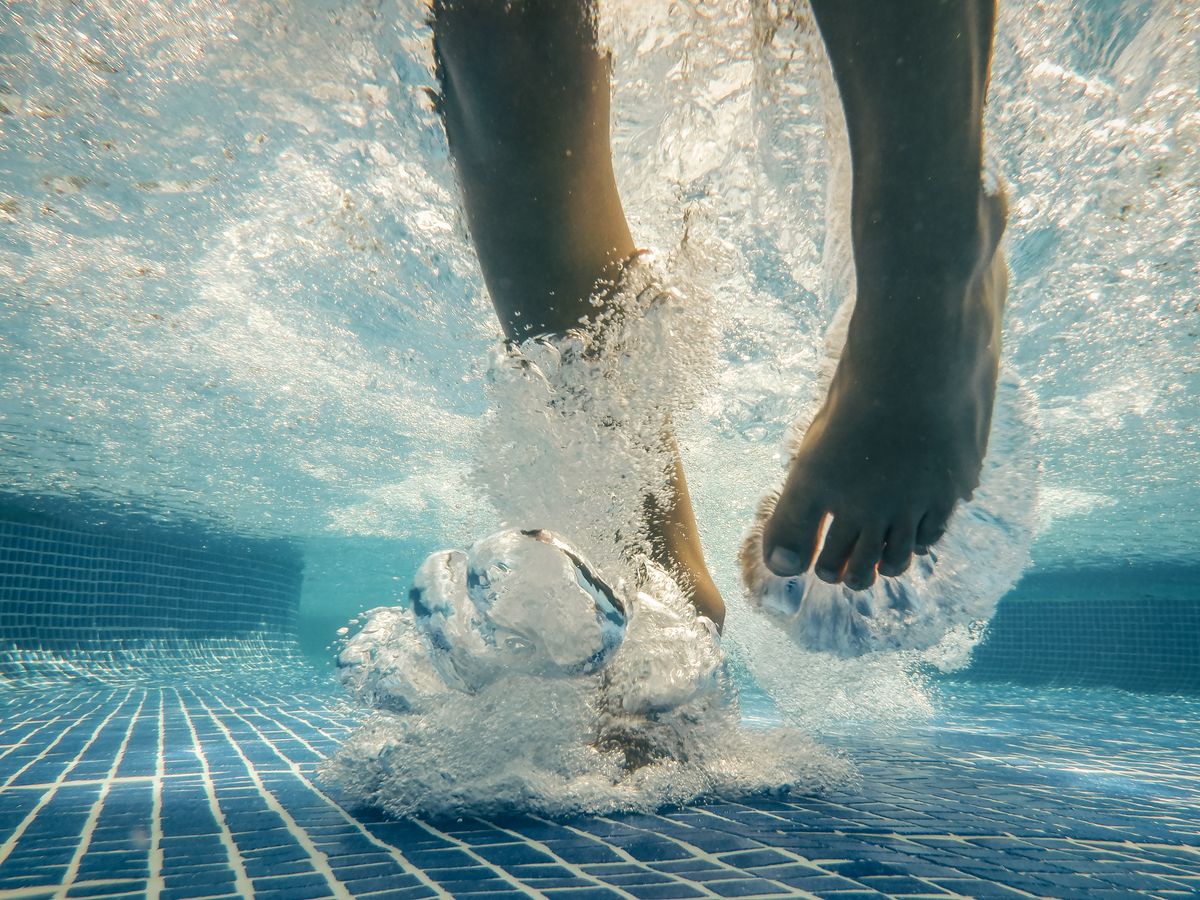 Feet seen underwater in a pool, which looks shallower thanks to refraction