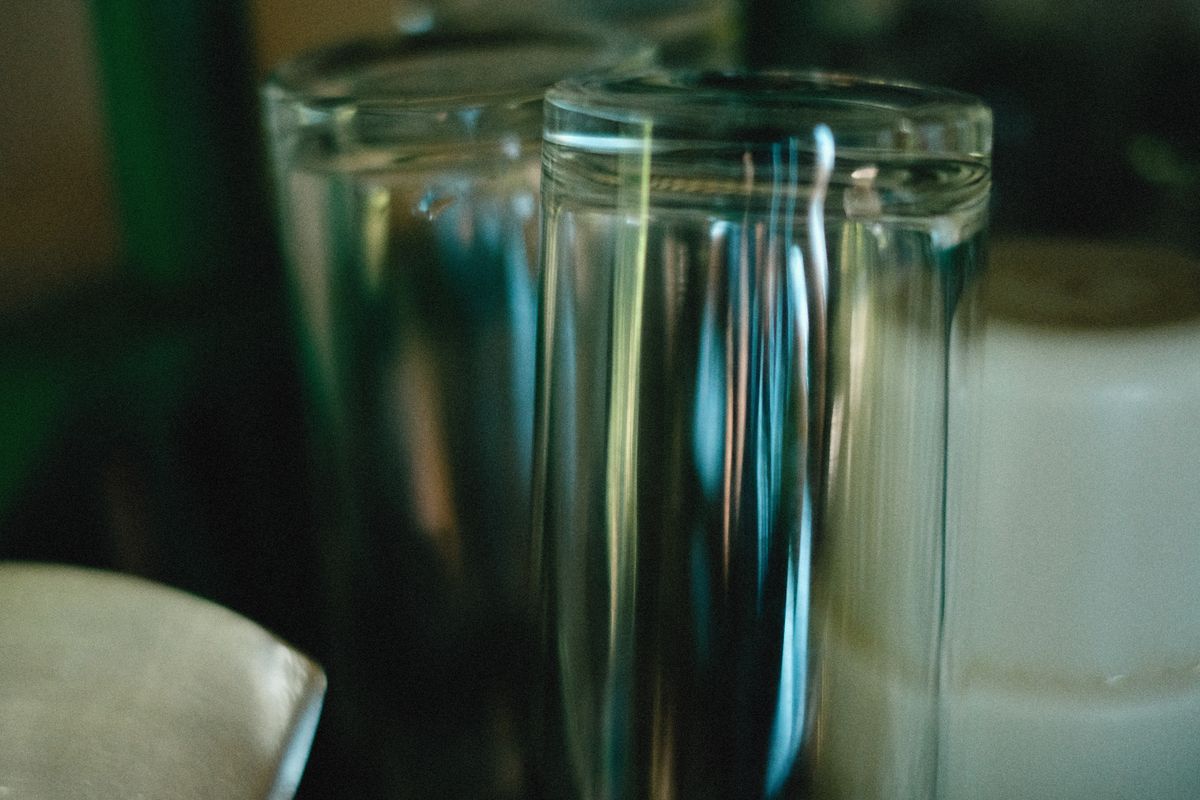 Two glasses on a table showing light bending through transparent surfaces, what causes refraction