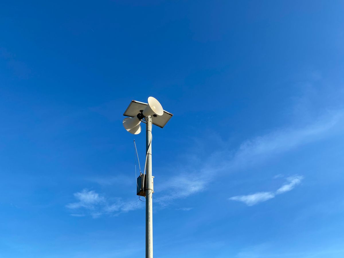 A communication tower with radio antennas against a blue sky demonstrating vertical and horizontal polarisation