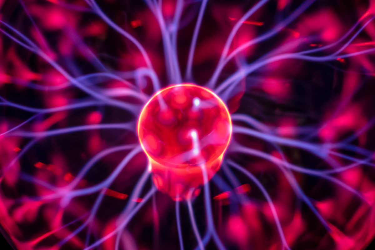 A plasma globe with glowing electric streams, illustrating the gas-discharge principle used in gas lasers
