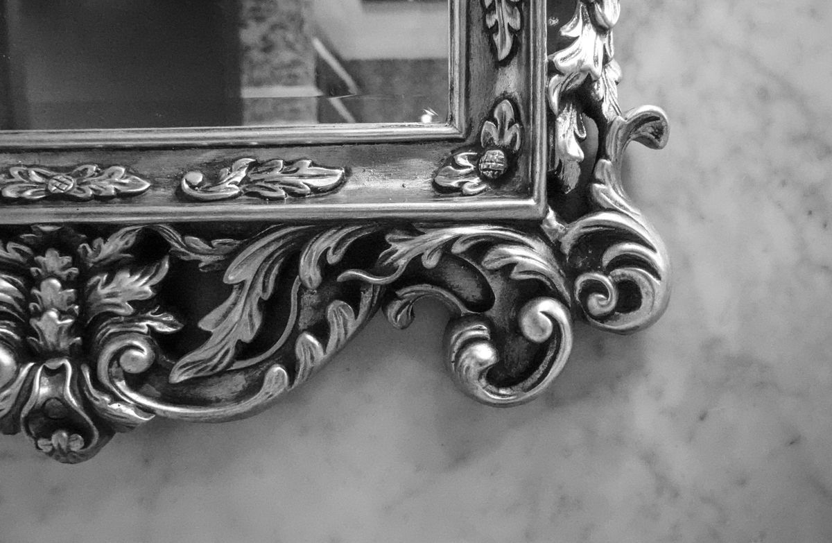 Close-up of a decorative baroque mirror frame showing what happens when light hits a mirror surface