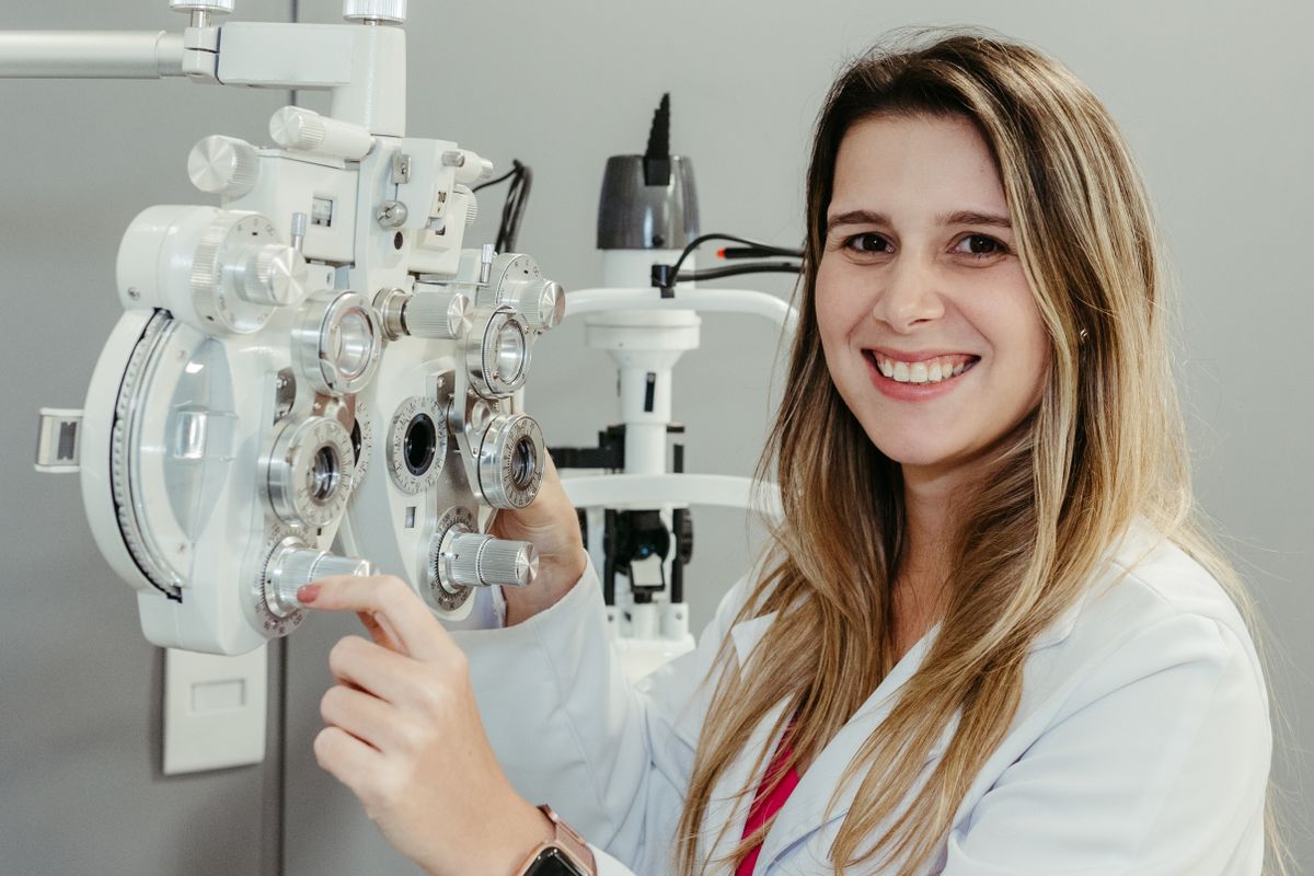 An optician using a phoropter to fit lenses, applied optics at work