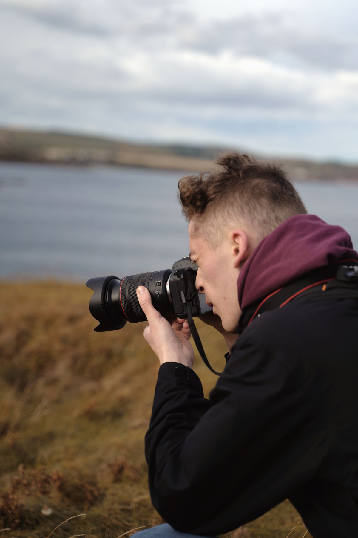 A male photographer with a camera on a tripod in a mountain landscape, demonstrating outdoor CPL filter use