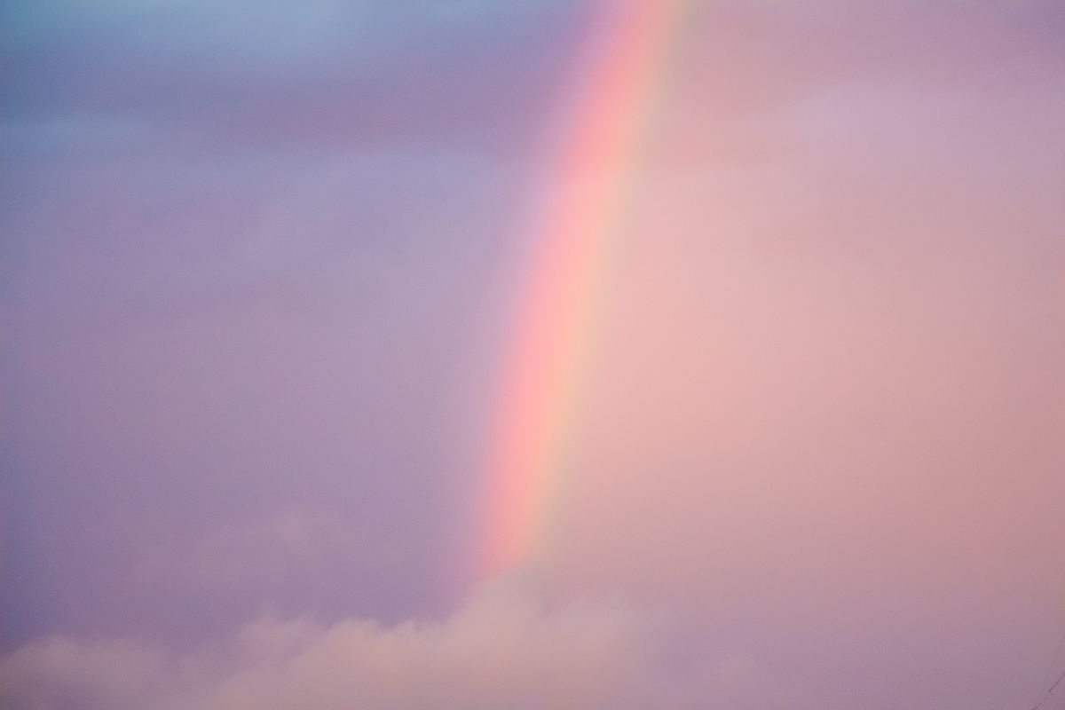 A serene pastel rainbow stretching across a soft cloudy sky in tranquil weather