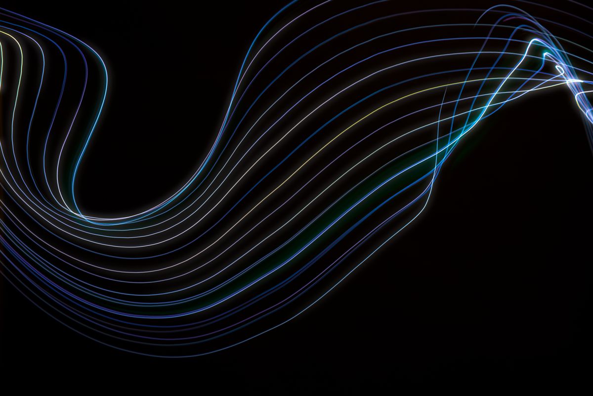 Colorful abstract light waves on a dark background illustrating the curved spherical wavefronts characteristic of Fresnel diffraction in the near-field regime