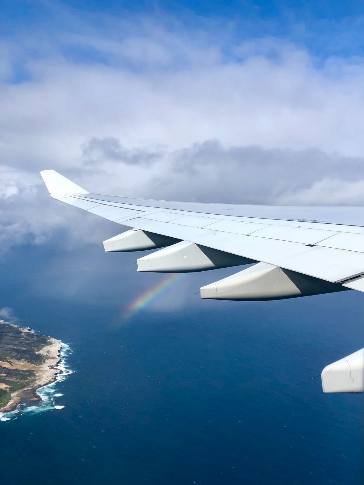 Airplane wing with a vibrant rainbow visible through the clouds, showing how aerial views reveal the full circle
