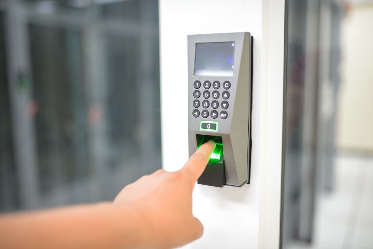 A person uses a fingerprint scanner for secure entry in a business setting
