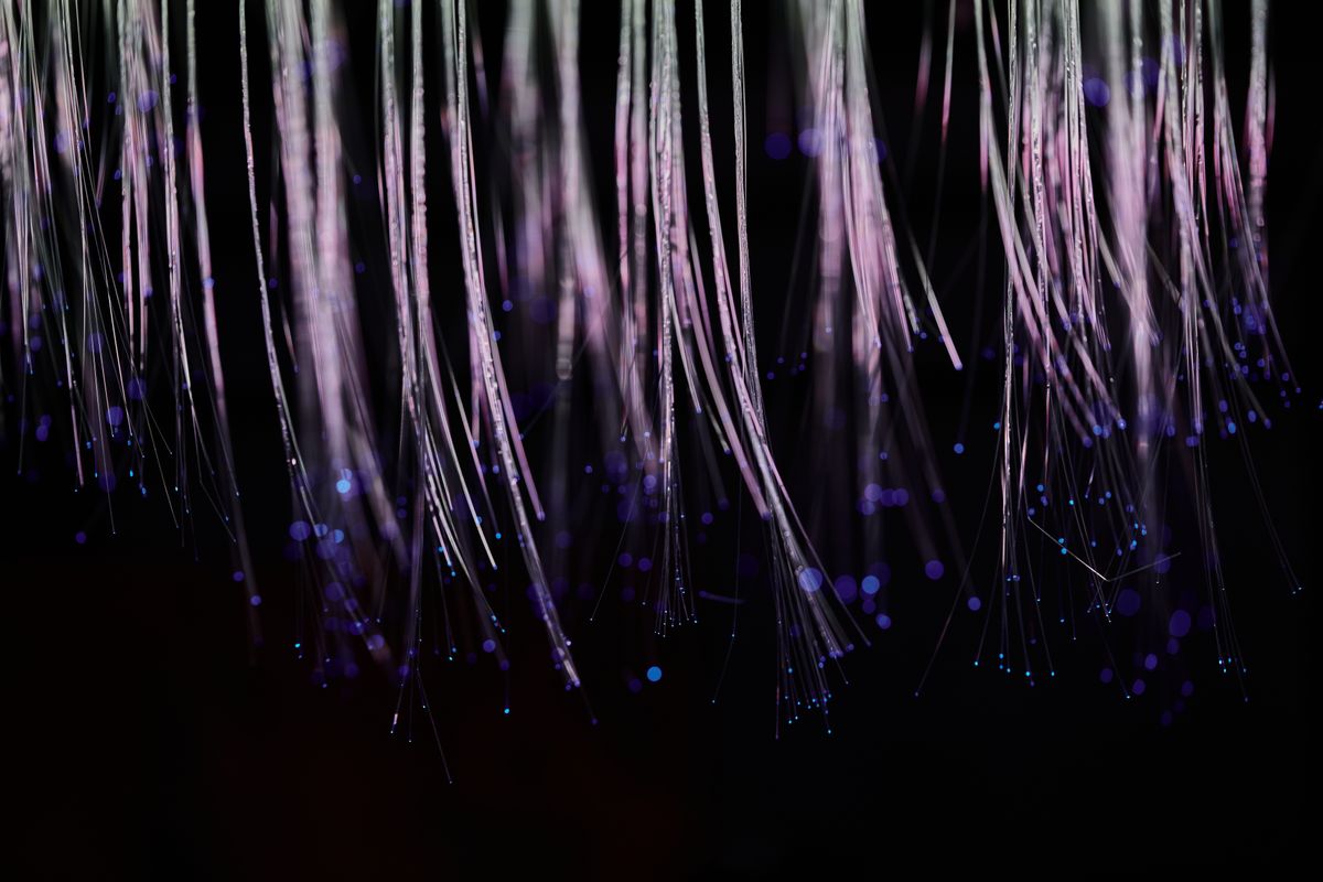 What is fiber optic cable made of: glowing fibre optic strands representing data transmission through the glass core of the cable