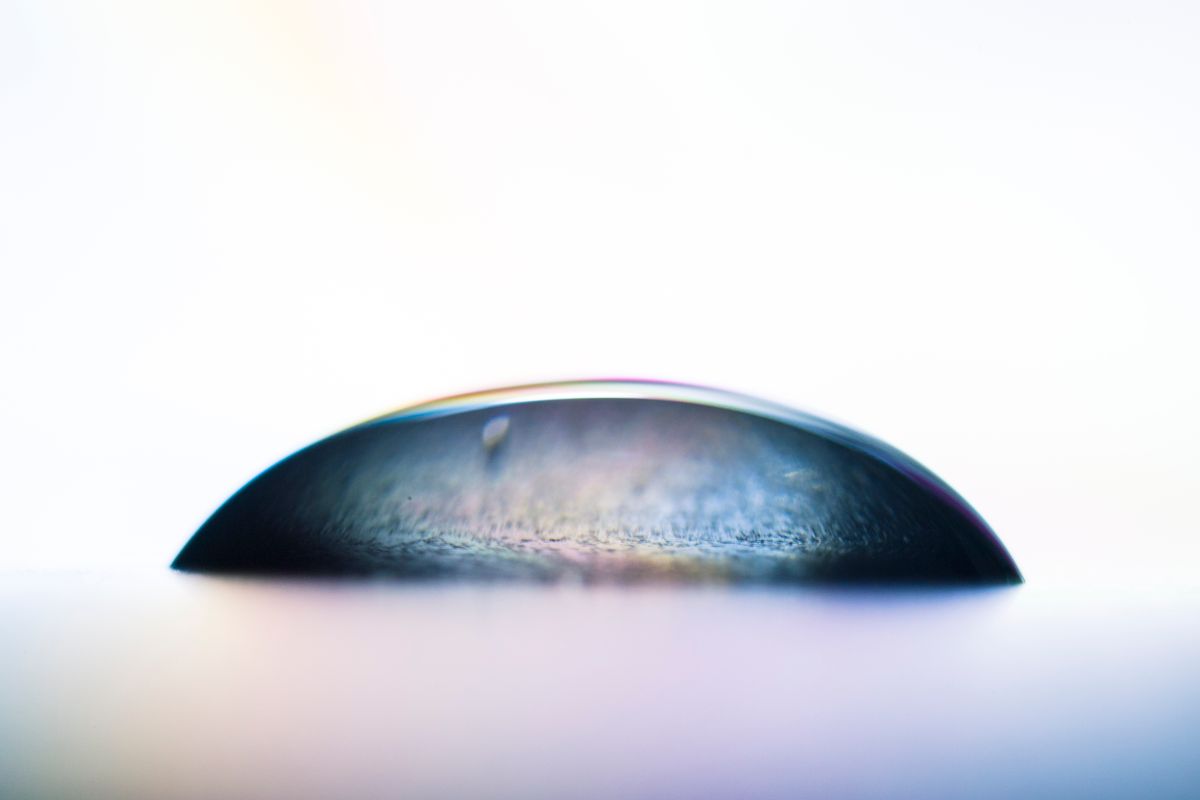Close-up of a water droplet creating a colourful refraction reflection on a surface