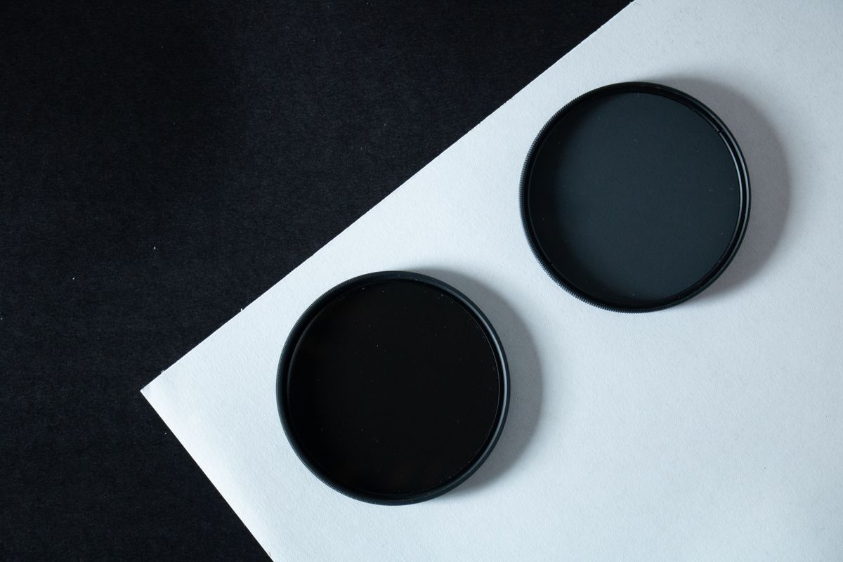 Two black circular filters on contrasting paper, representing camera lens filters and their physical design
