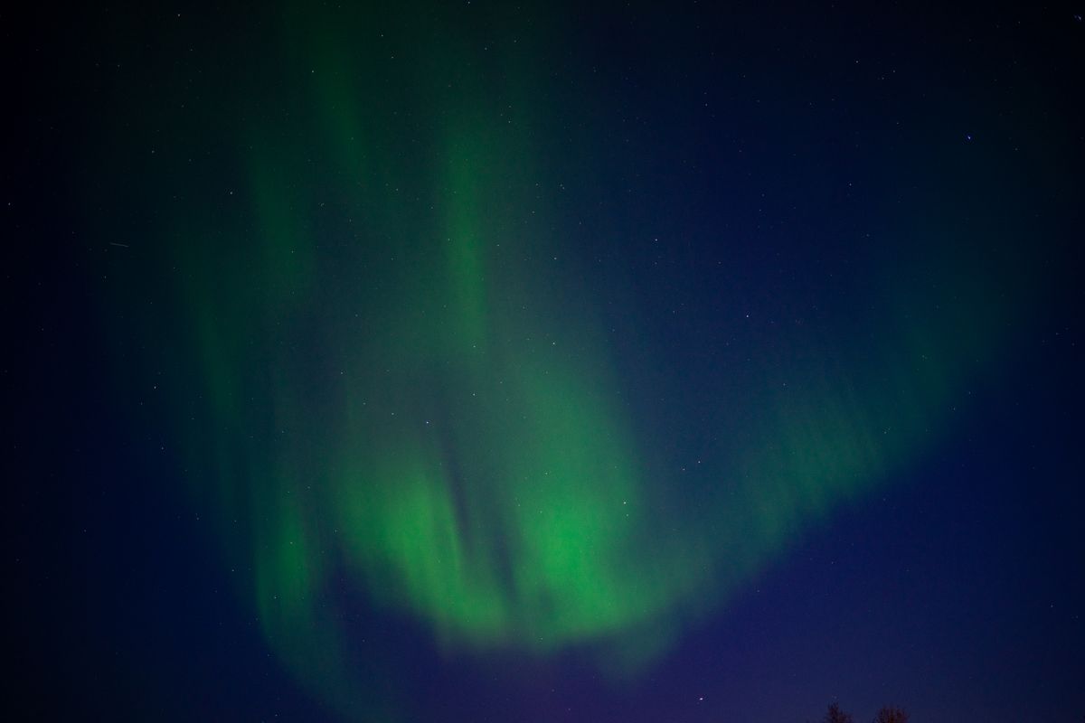 Green aurora borealis over a night landscape, natural light painted by the Sun