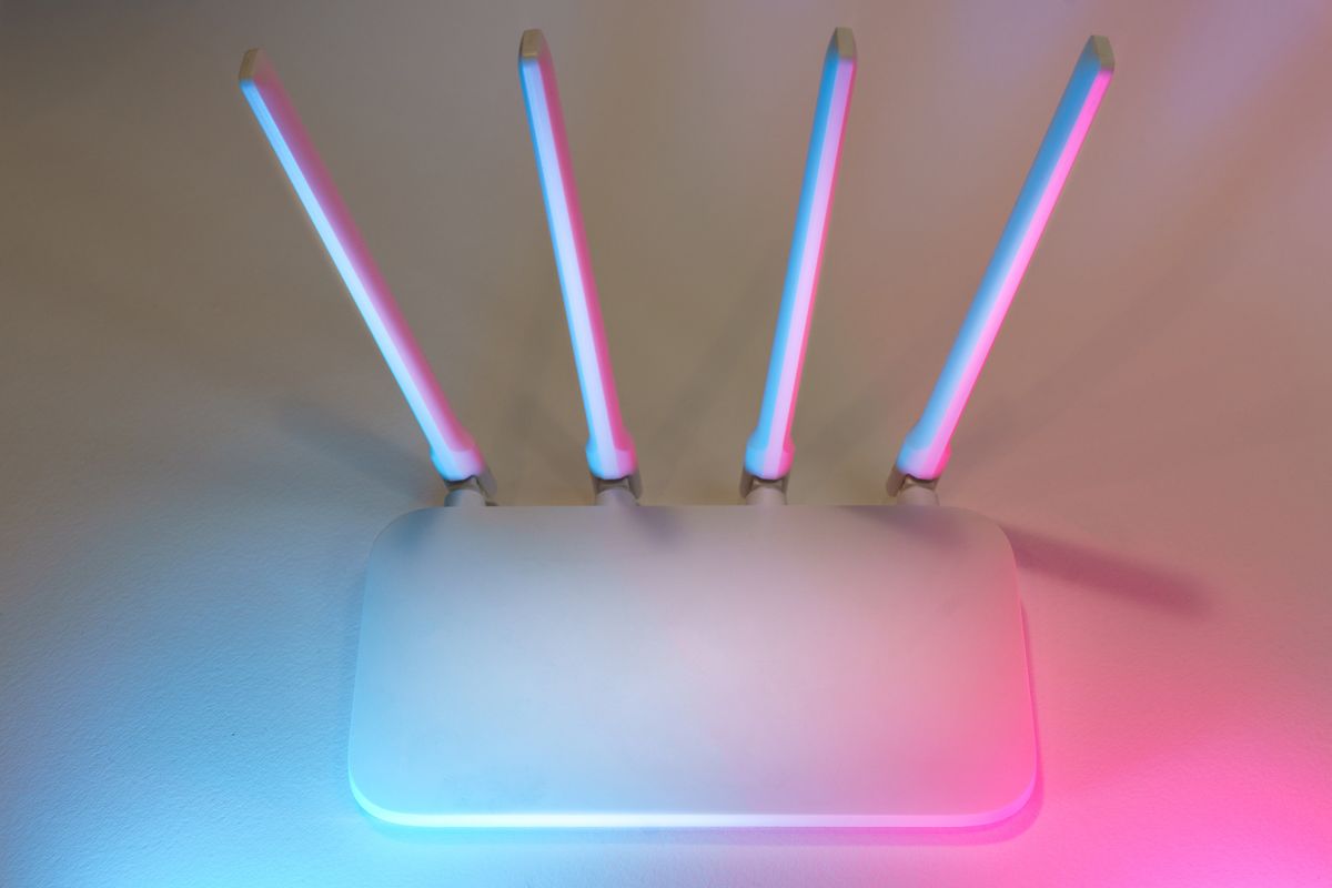What is fiber optic internet: a sleek white wireless router with antennas glowing blue and pink representing a modern fast home fibre setup