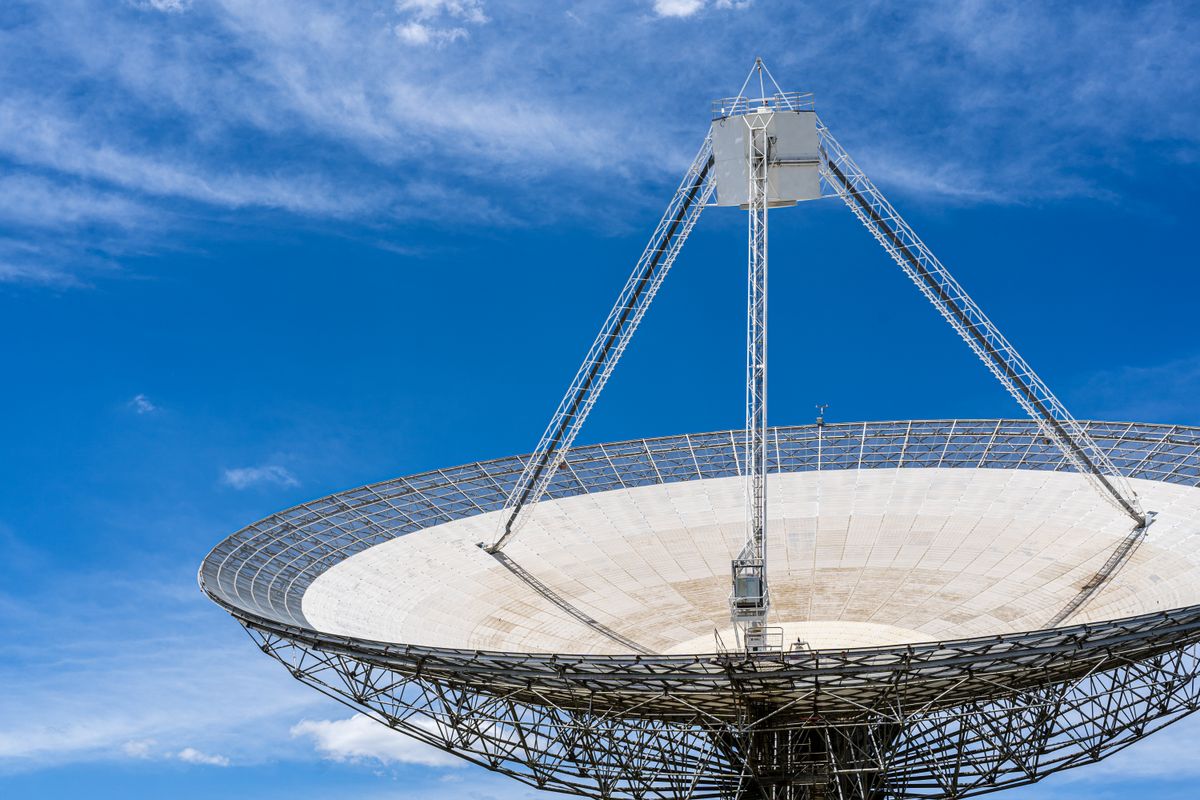 A large satellite dish against a blue sky, demonstrating how concave reflectors concentrate incoming signals at the focal point in the same way concave mirrors focus light
