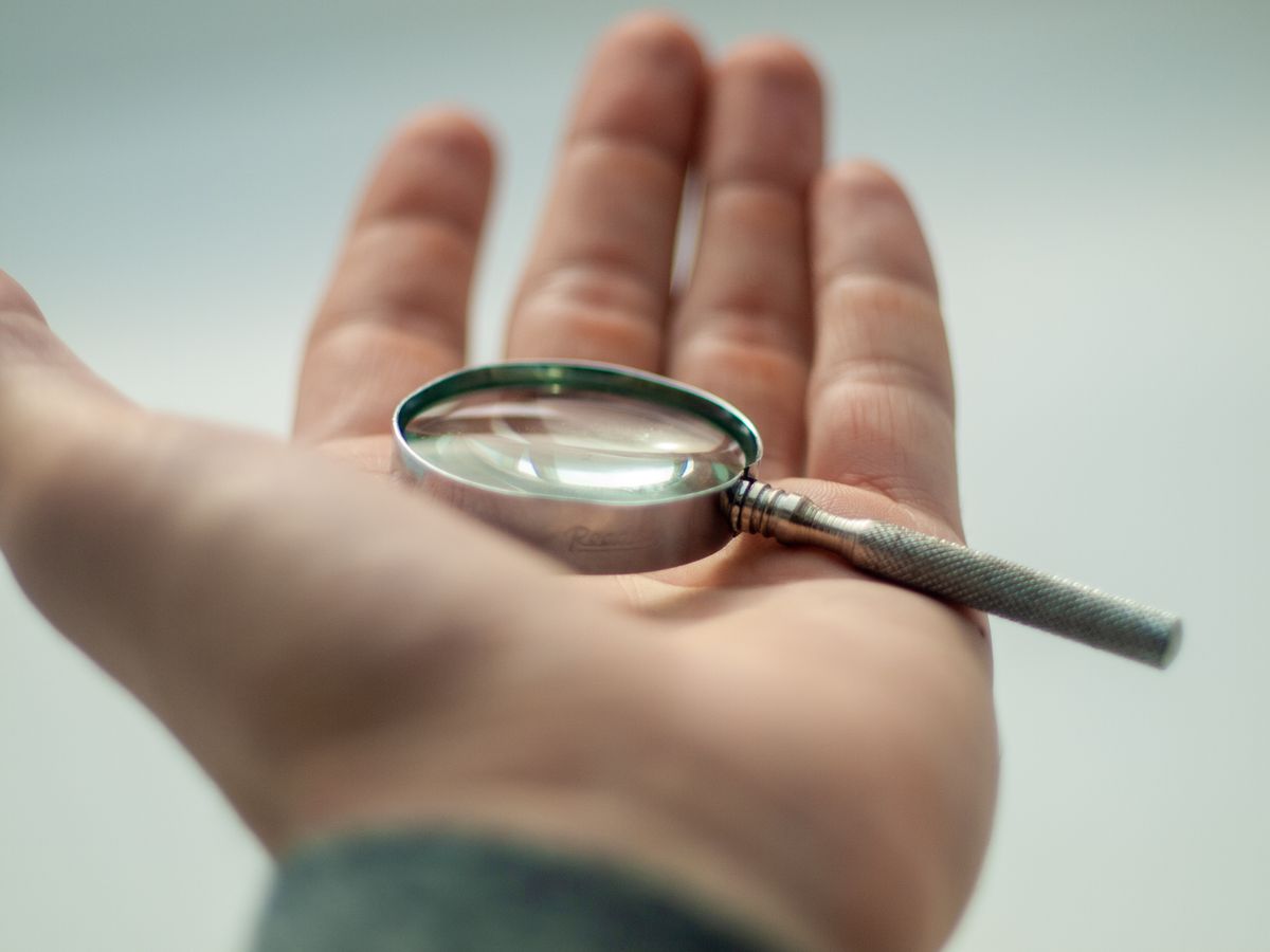 Hand holding a magnifying glass showing the convex lens shape with thicker centre and thinner edges