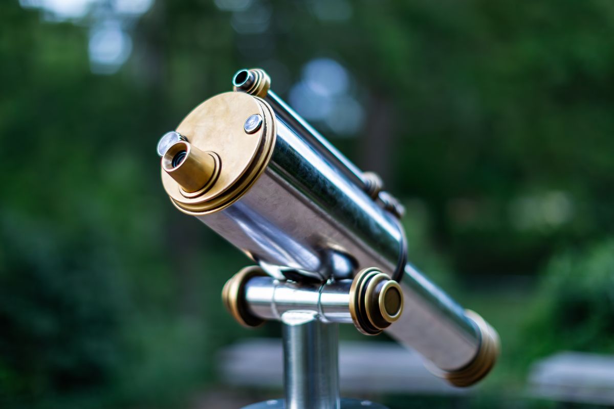 Outdoor brass telescope against a natural background, showing how lenses and mirrors are combined in optical instruments