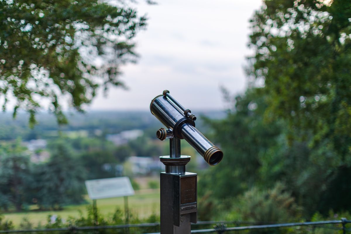 A public telescope pointing towards a scenic landscape, showing a use of convex lenses
