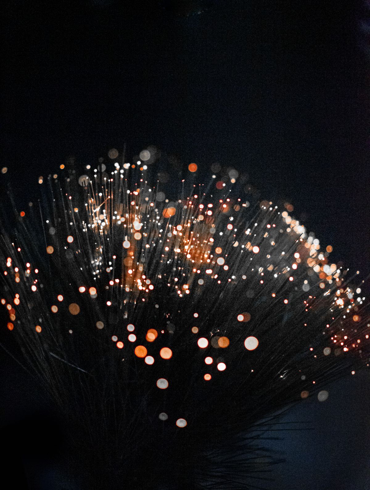 An artistic shot of fiber optic lights on a dark background creating a bokeh effect with vivid colors, illustrating what is optical fiber used in decorative and lighting applications