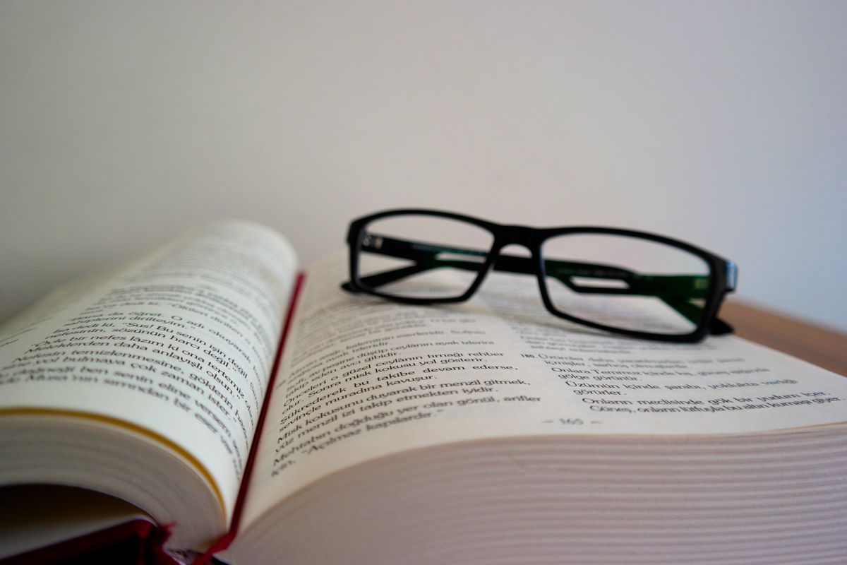 Eyeglasses resting on an open book, lenses that work by refraction