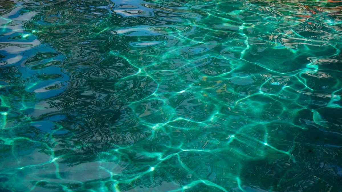 Sunlight reflecting off a swimming pool surface with ripples, showing refraction of light in water