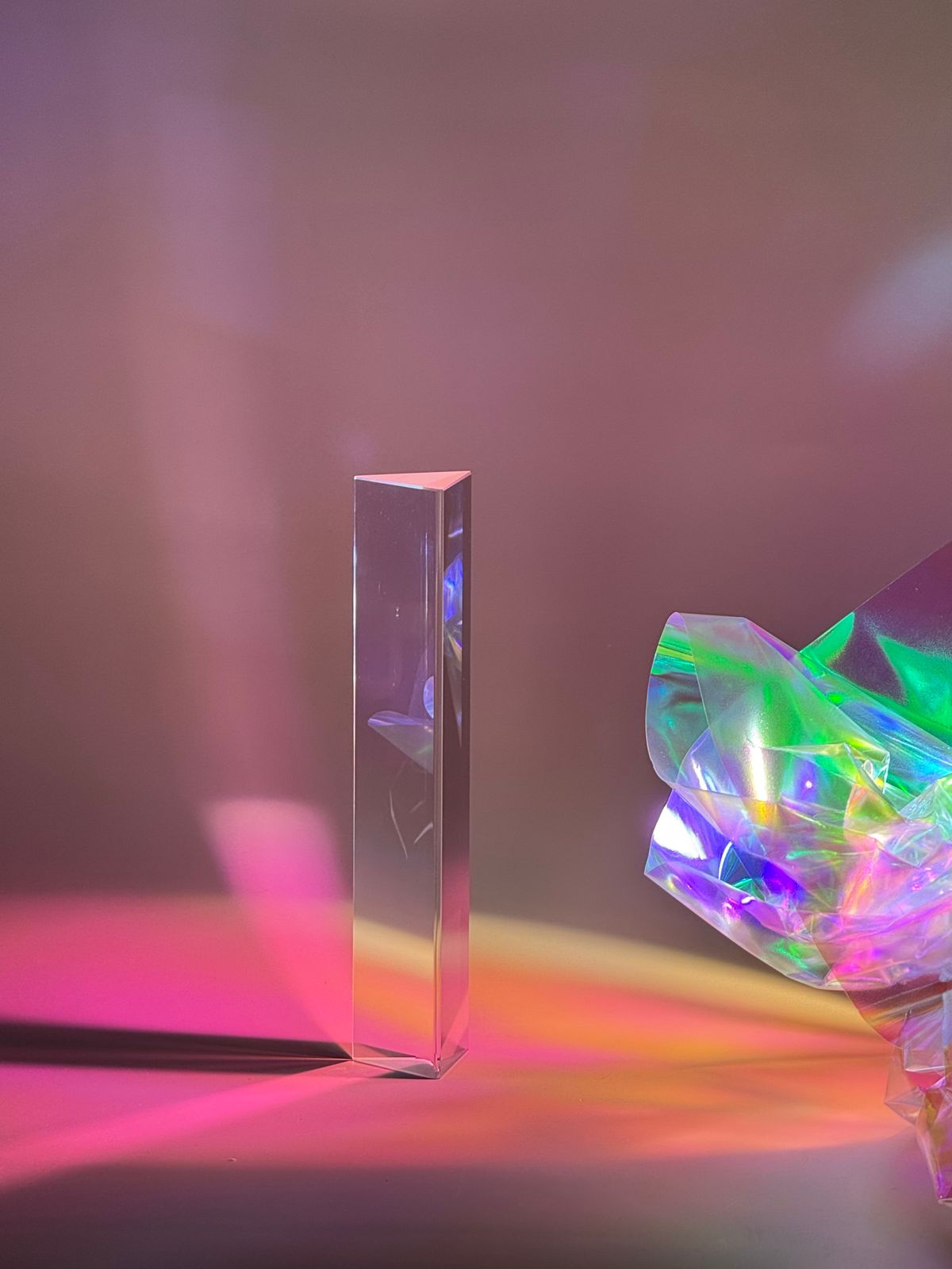 Tall glass prism casting colourful light reflections, demonstrating refraction through glass
