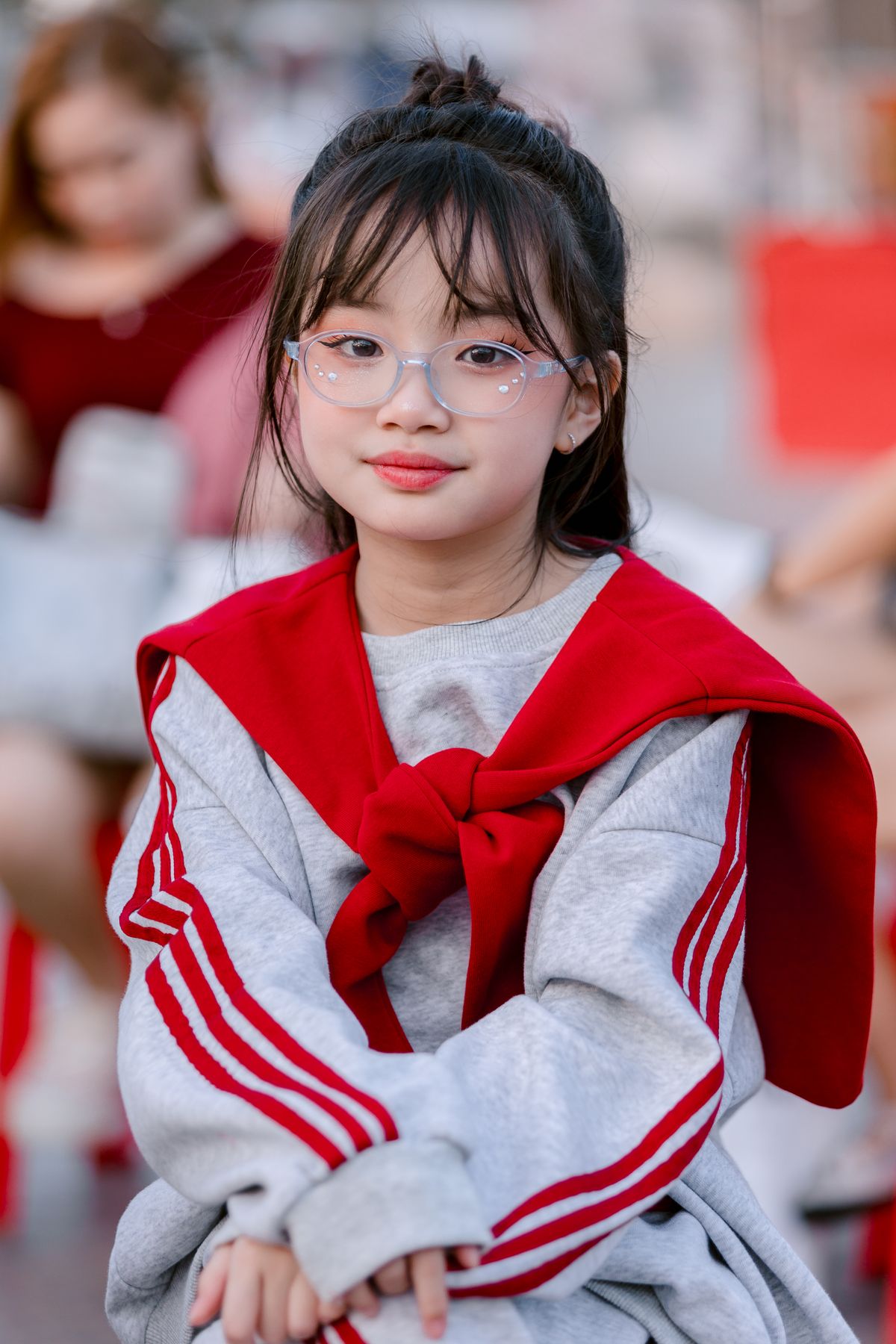 Charming young girl with glasses sitting outdoors, showing how concave lens for myopia helps children see clearly