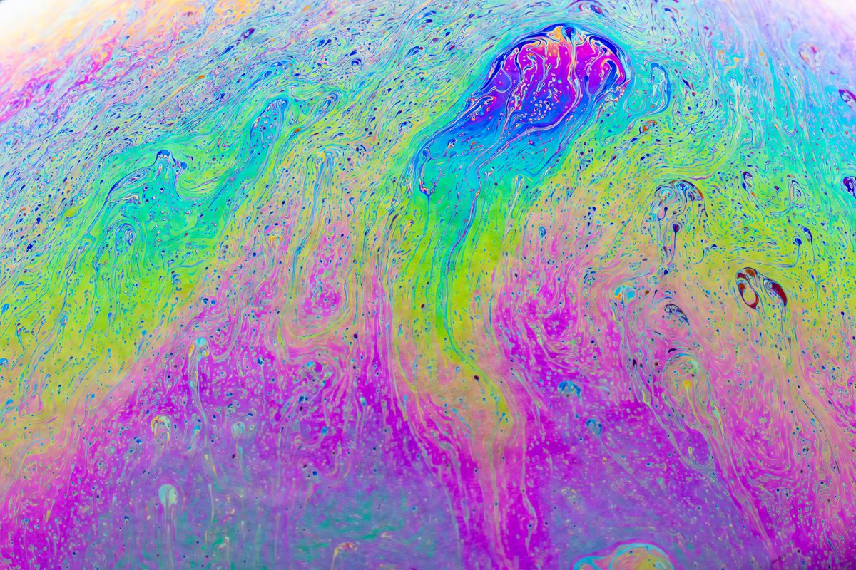 Close-up of a soap bubble showing rainbow-colored thin film interference patterns on its surface