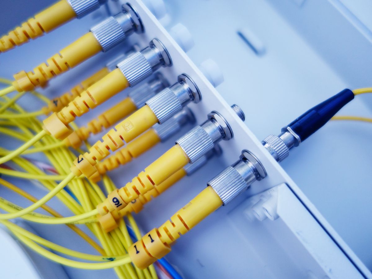 Close-up of yellow fiber optic cables in a network server showcasing fast data transfer from the Corning era to modern communication