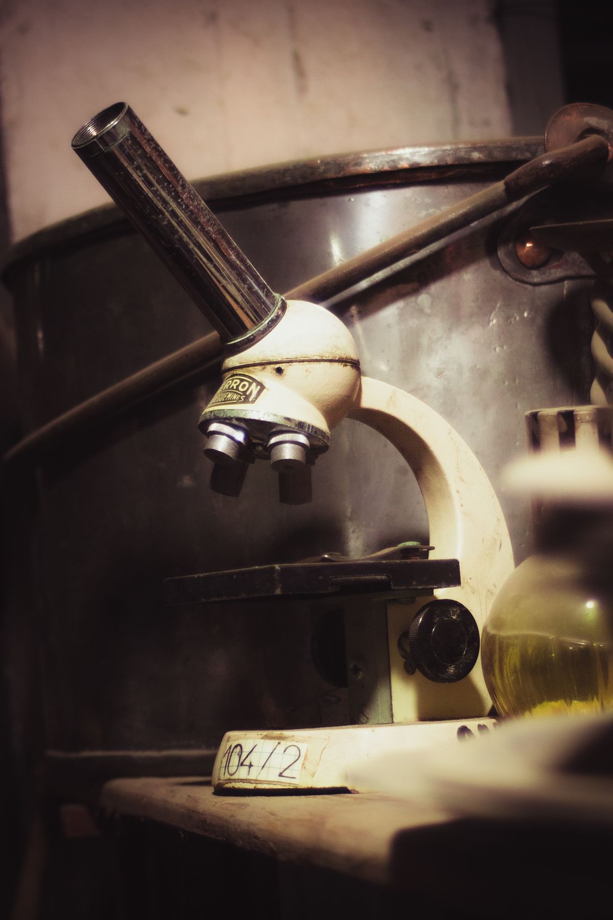 A vintage microscope on an old table in a dimly lit laboratory