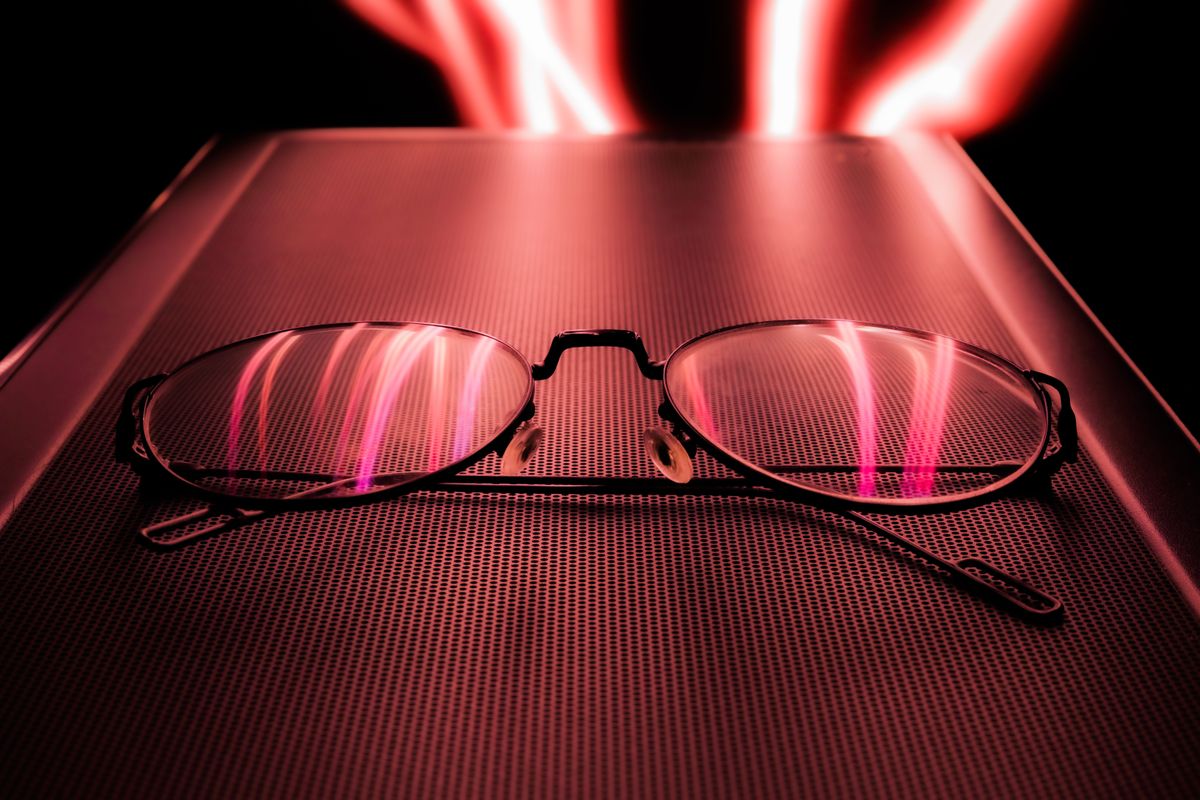 Artistic still life of eyeglasses reflecting mesmerizing red light trails, illustrating how laser technology creates precise light patterns
