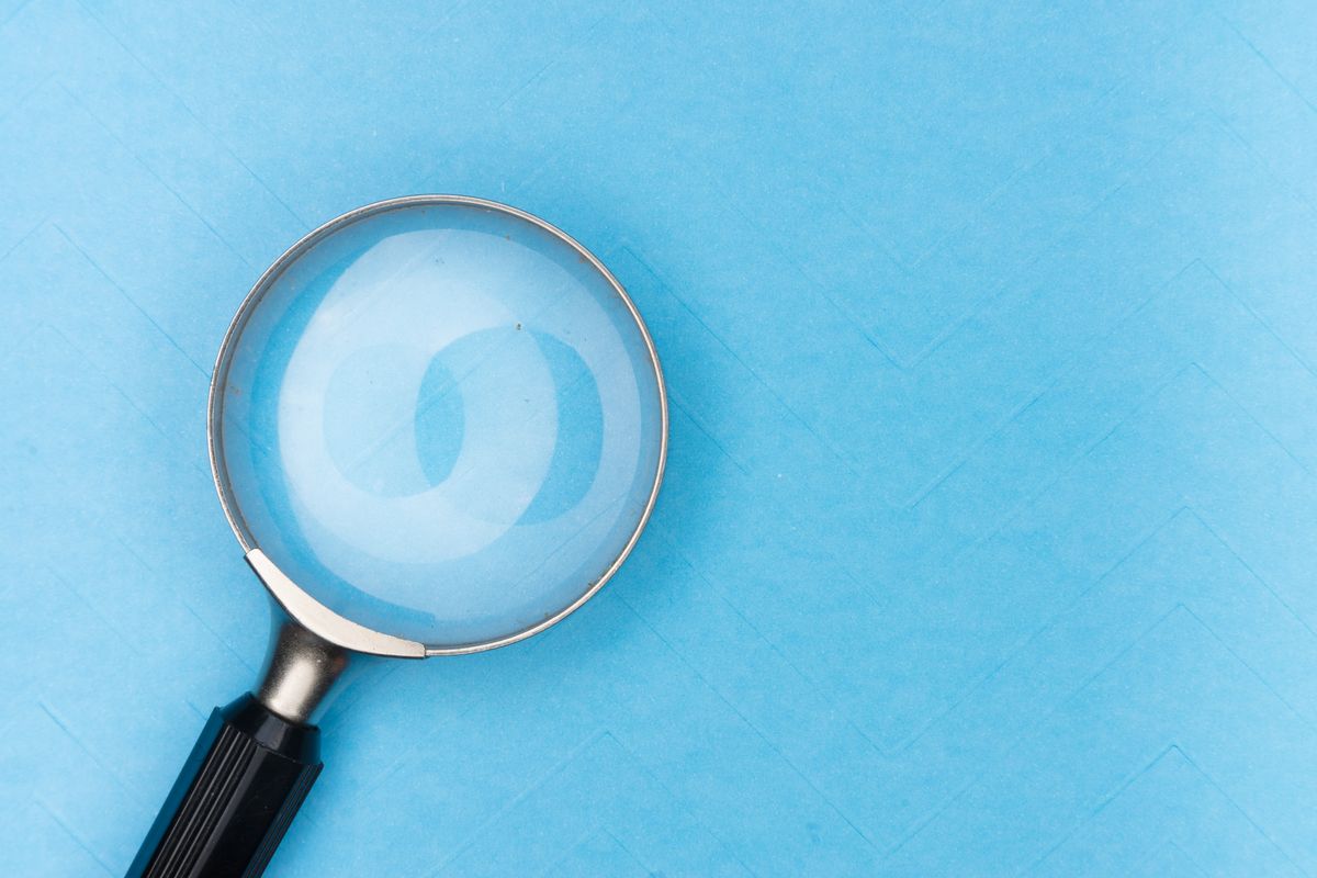 Close-up of a magnifying glass lens on a blue surface showing how refraction bends light