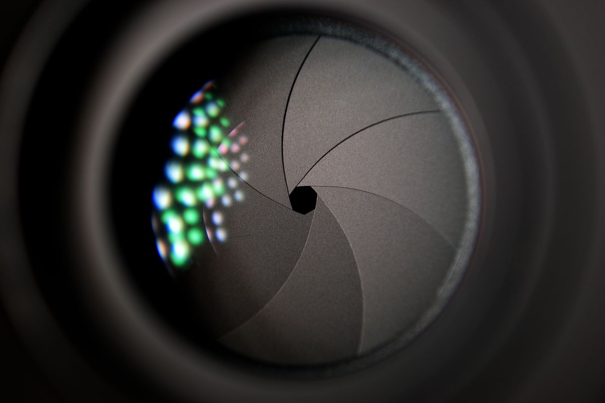 Detailed close-up of a camera lens aperture showing the mechanical blades that create the opening through which light is diffracted at small apertures
