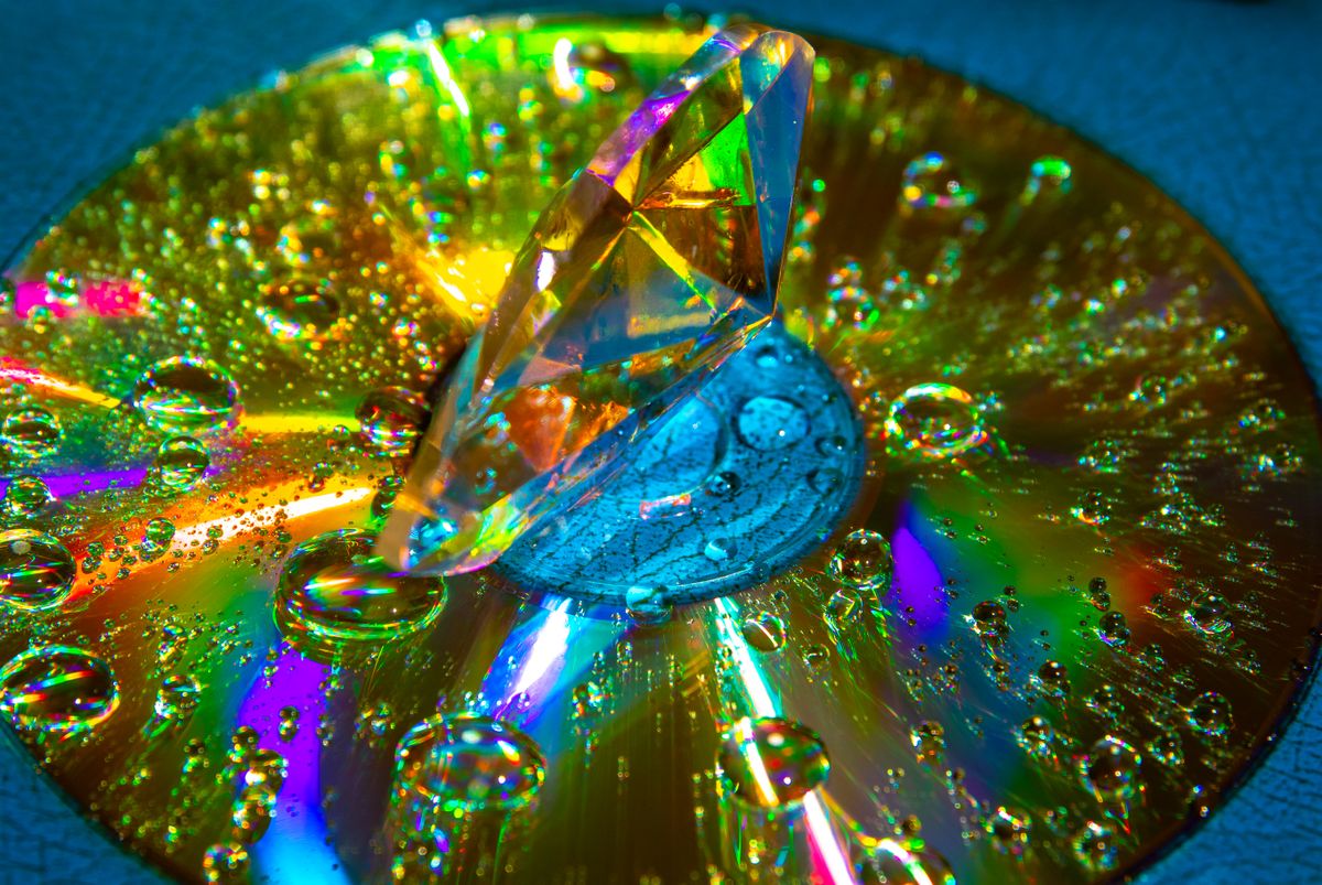 Close-up of a reflective disc surface showing rainbow diffraction patterns from light hitting the grooves