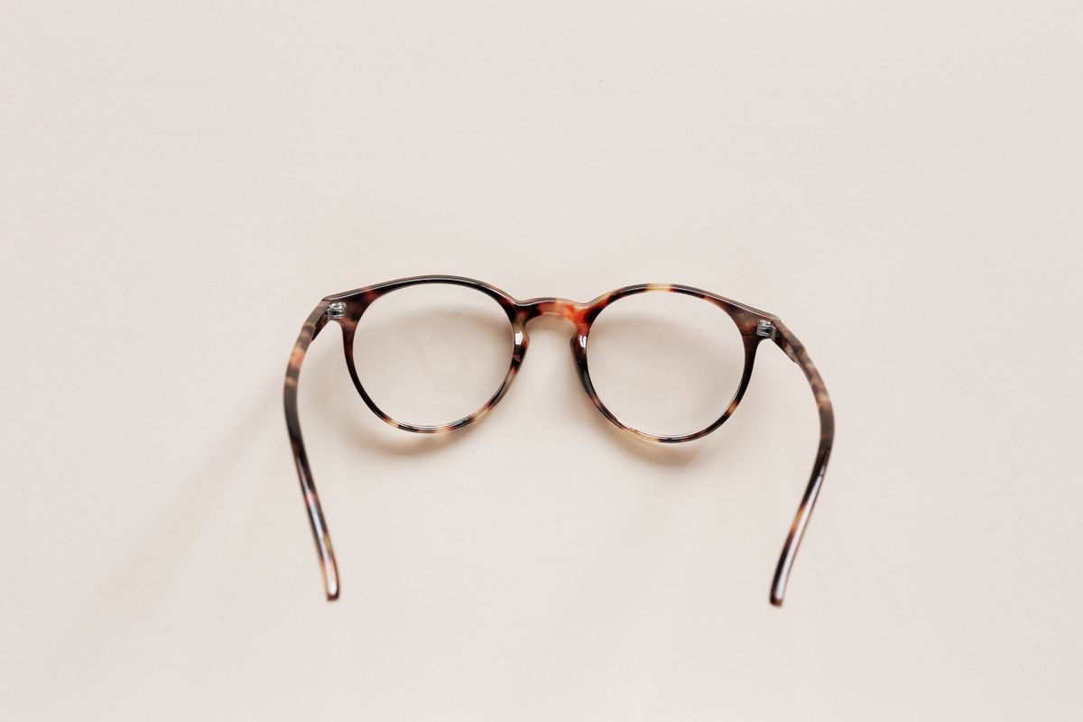 Round tortoise-shell spectacles on a white tabletop, representing eyeglasses that use convex or concave lenses for vision correction