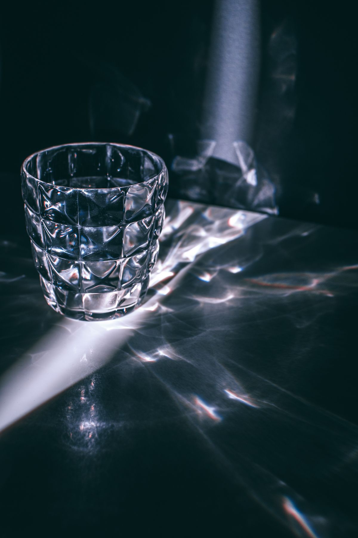 Faceted glass showing bright sunbeam and refracted rays of light in a dark room