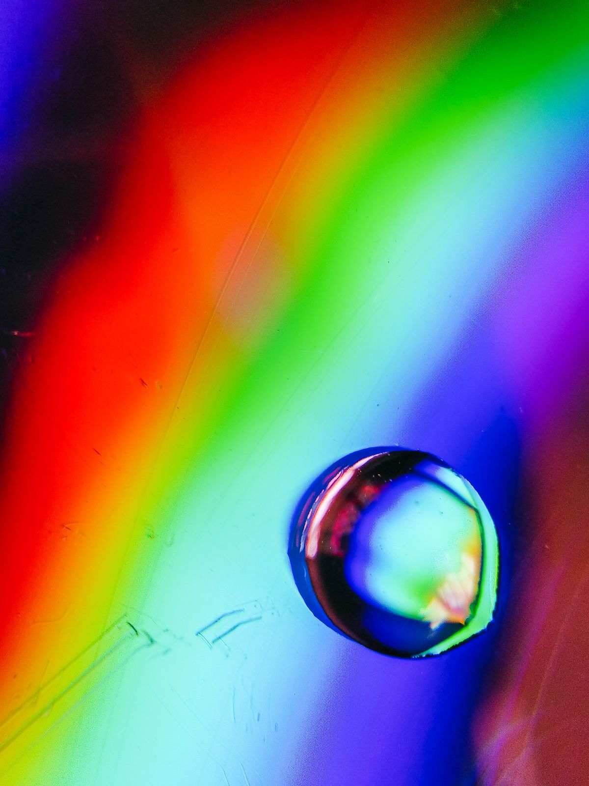 A close-up macro of a water droplet acting as a tiny prism refracting rainbow colours