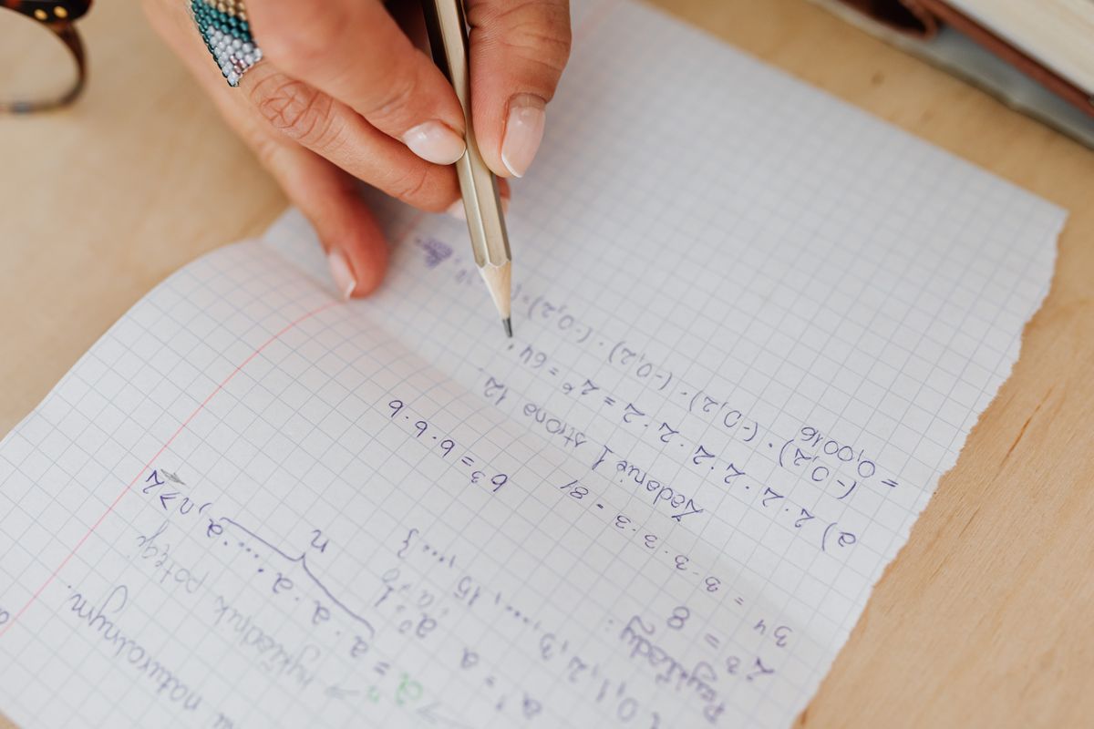 Working through an optics formulas cheat sheet by hand, writing equations on grid paper