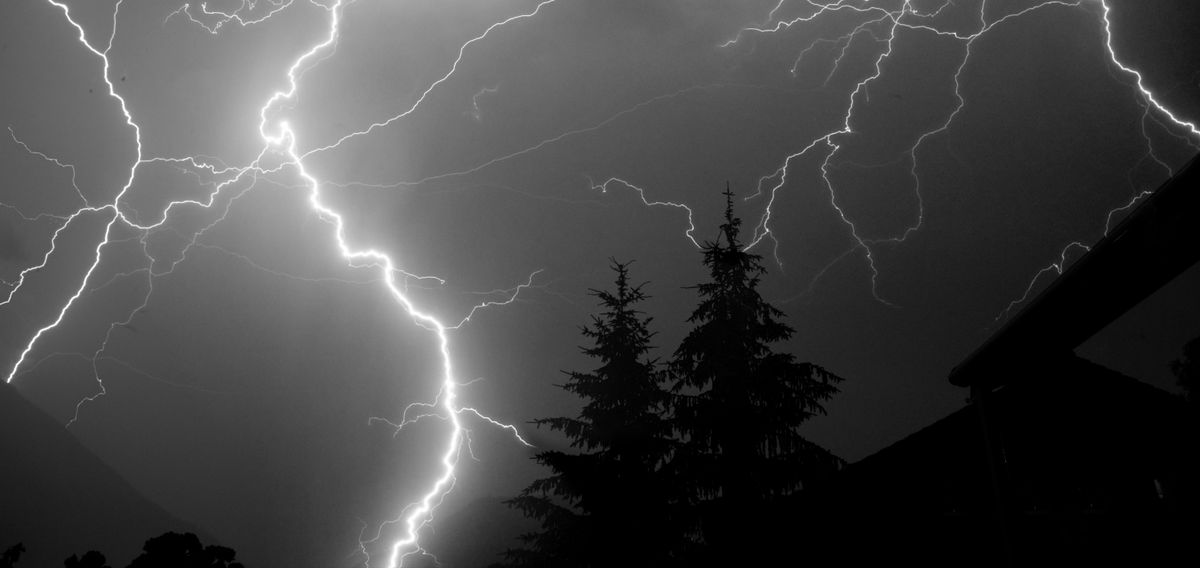 A lightning bolt over trees at night, showing how fast light reaches your eyes