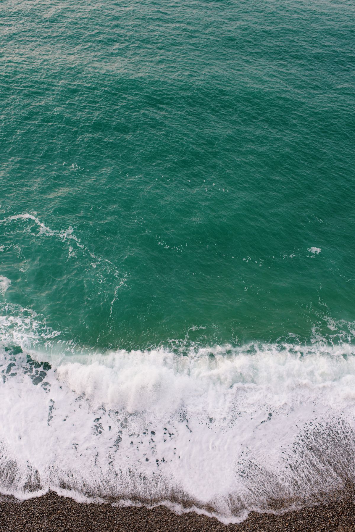 Ocean waves approaching a shoreline at an angle, showing wave refraction as they bend toward the beach