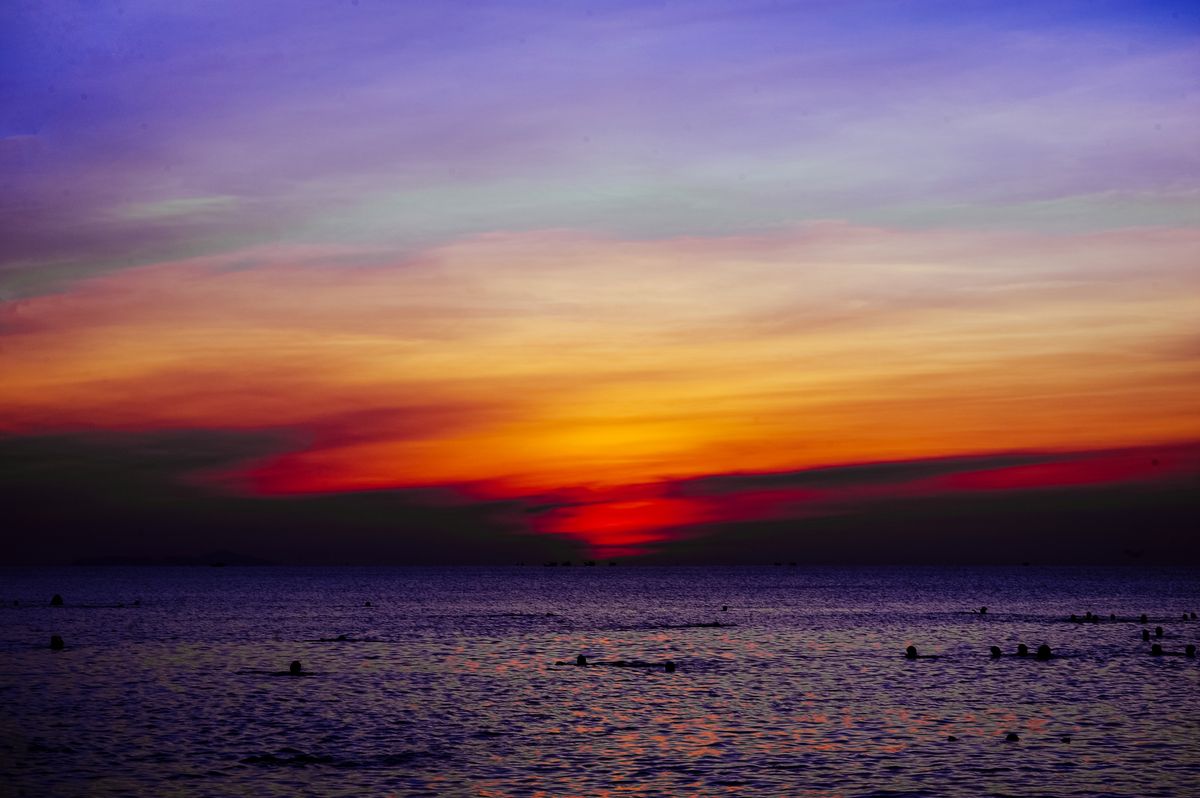 Sun setting over the ocean horizon, appearing flattened and oval due to atmospheric refraction