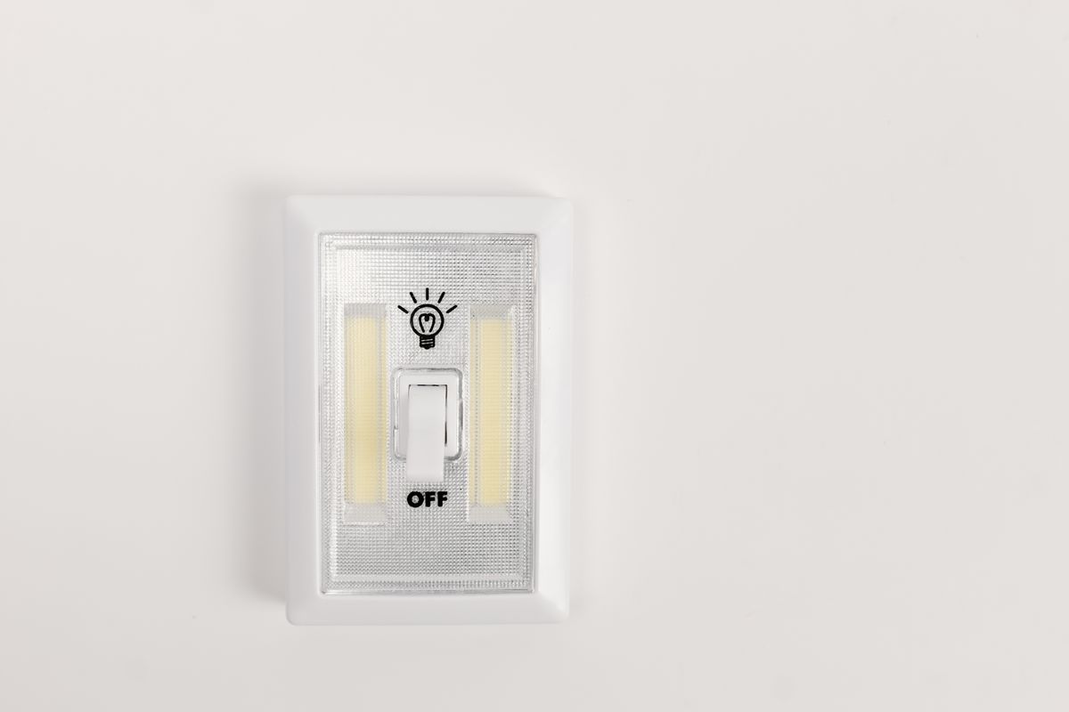 A single light switch on a white wall in the off position