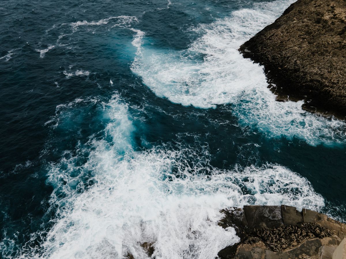 Ocean waves spreading after passing through a harbour entrance, illustrating how diffraction bends and spreads waves around obstacles