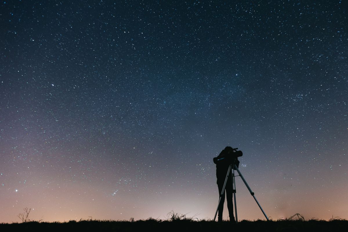 A person looking through a telescope, an optical system that gathers light