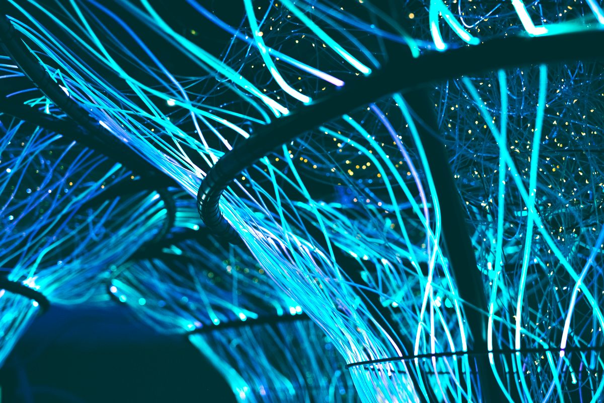 Glowing neon blue optical fibres representing the finished fibre product after the drawing process