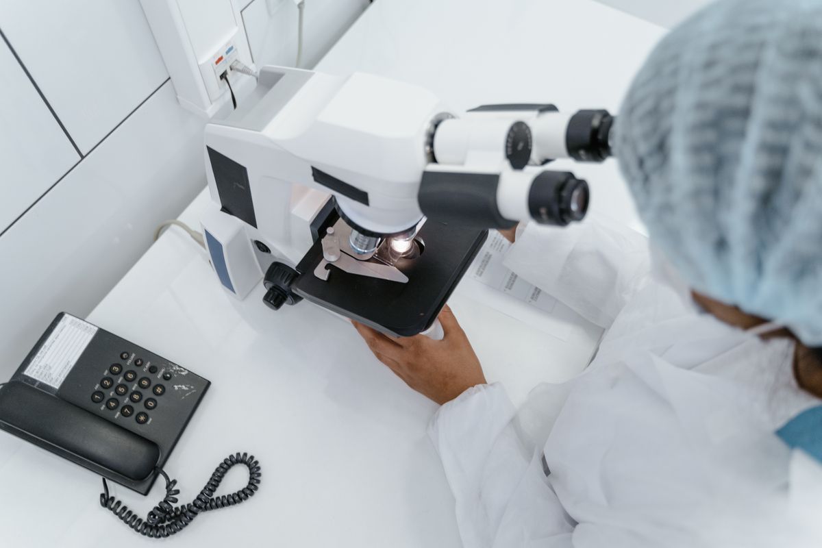 Scientist using a microscope in a laboratory demonstrating the practical use of optical instruments for research